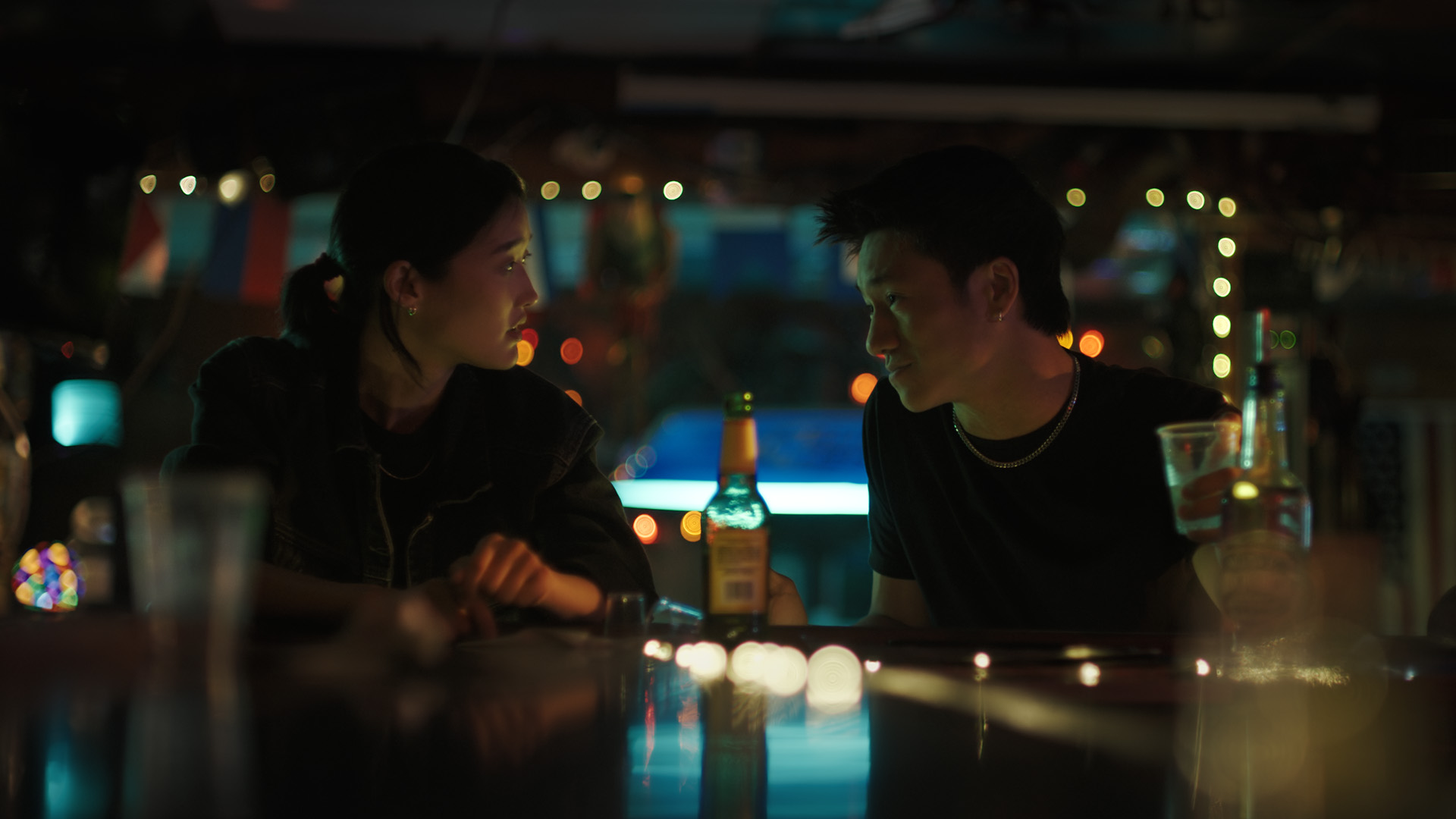 Asian woman and man talking in a dimly lit bar